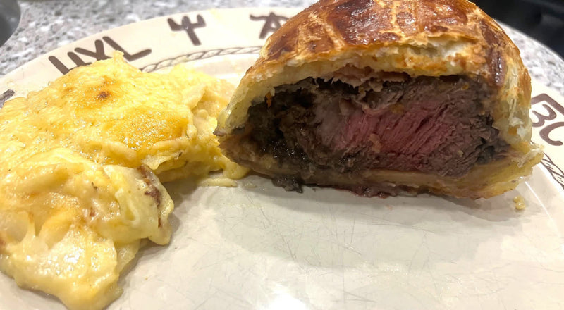 Beef wellington sliced open next to potato gratin