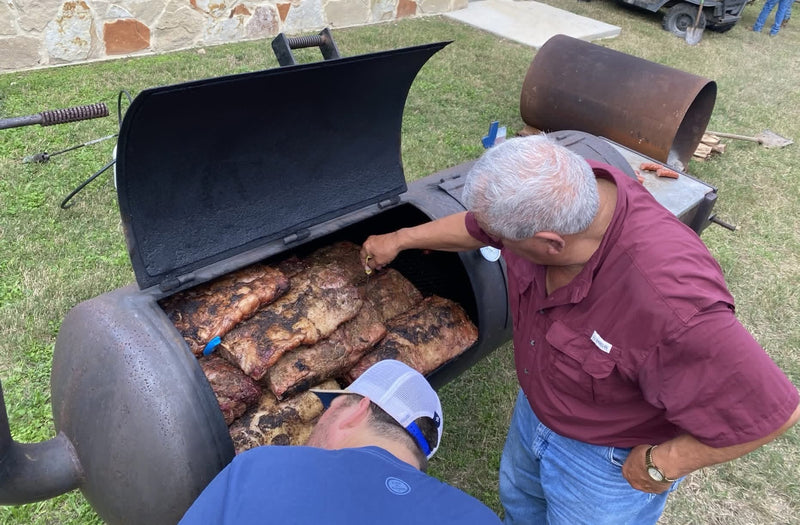 Ribs on an offset smoker being tended to