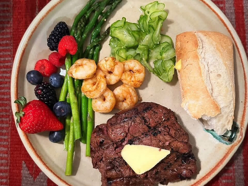 Plate with steak, shrimp, asparagus, and berries